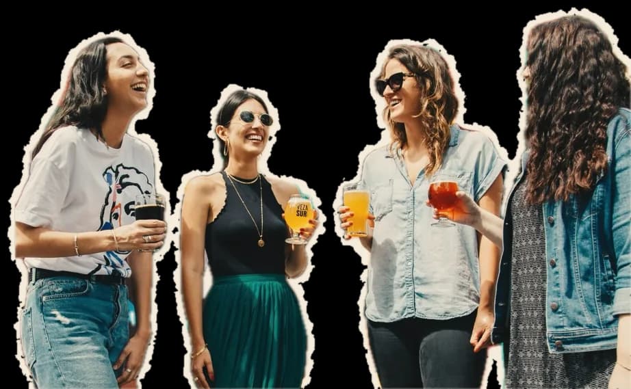 Four friends laughing together, drinks in hand
